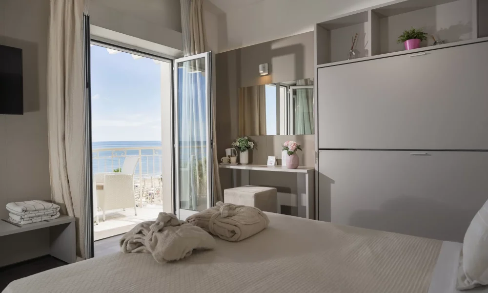 Camera d'albergo moderna con balcone vista mare e letti preparati.