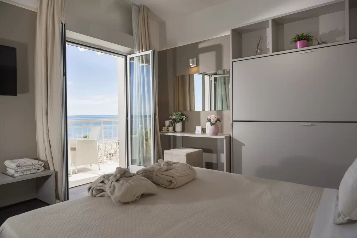 Camera d'albergo moderna con balcone vista mare e letti preparati.