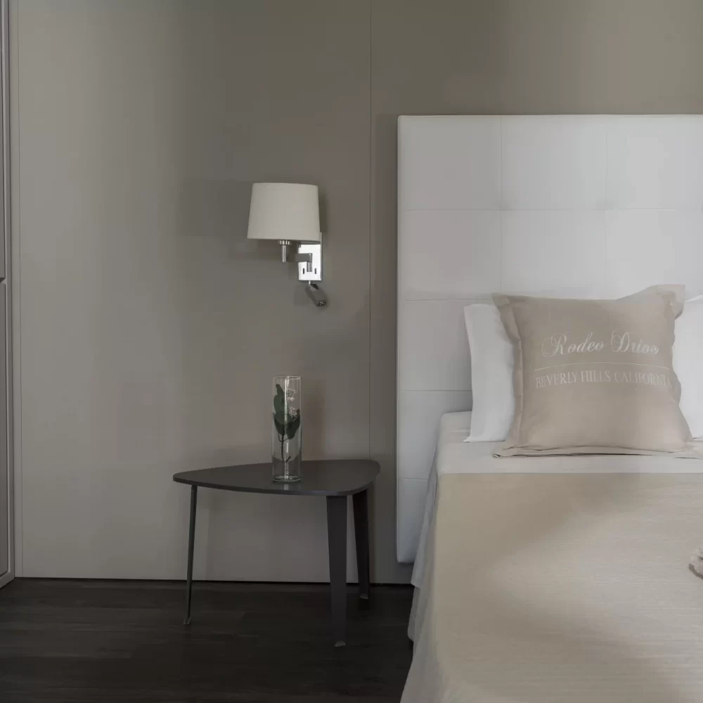 Modernes Schlafzimmer mit einem grauen Nachttisch, Bett und dekorativen Kissen.