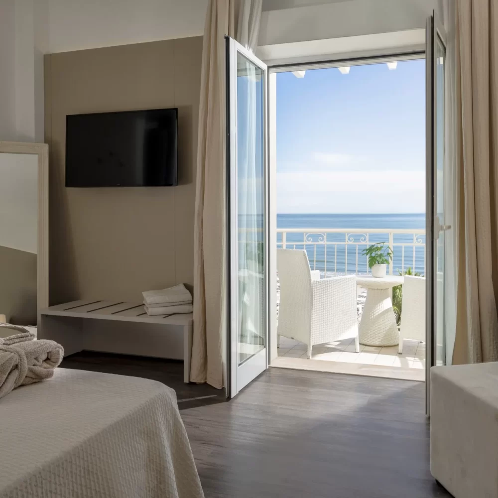 Helles Hotelzimmer mit Balkon und Meerblick.