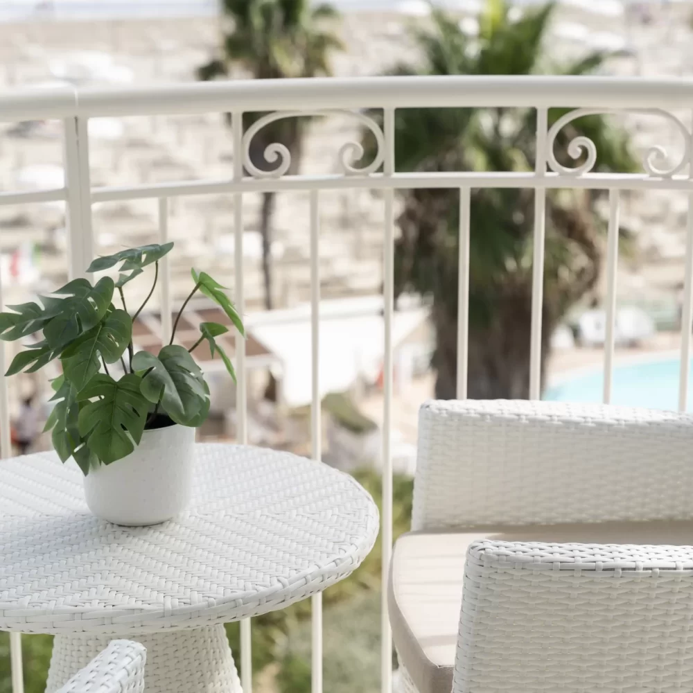 Balcone con tavolino bianco, pianta e vista sul mare.