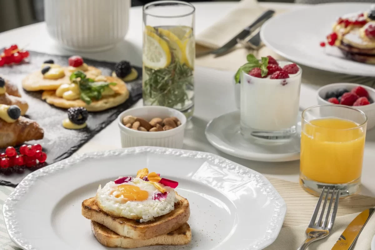 Ein elegantes Frühstück mit Spiegel ei auf Toast, Saft und verschiedenen Beilagen.