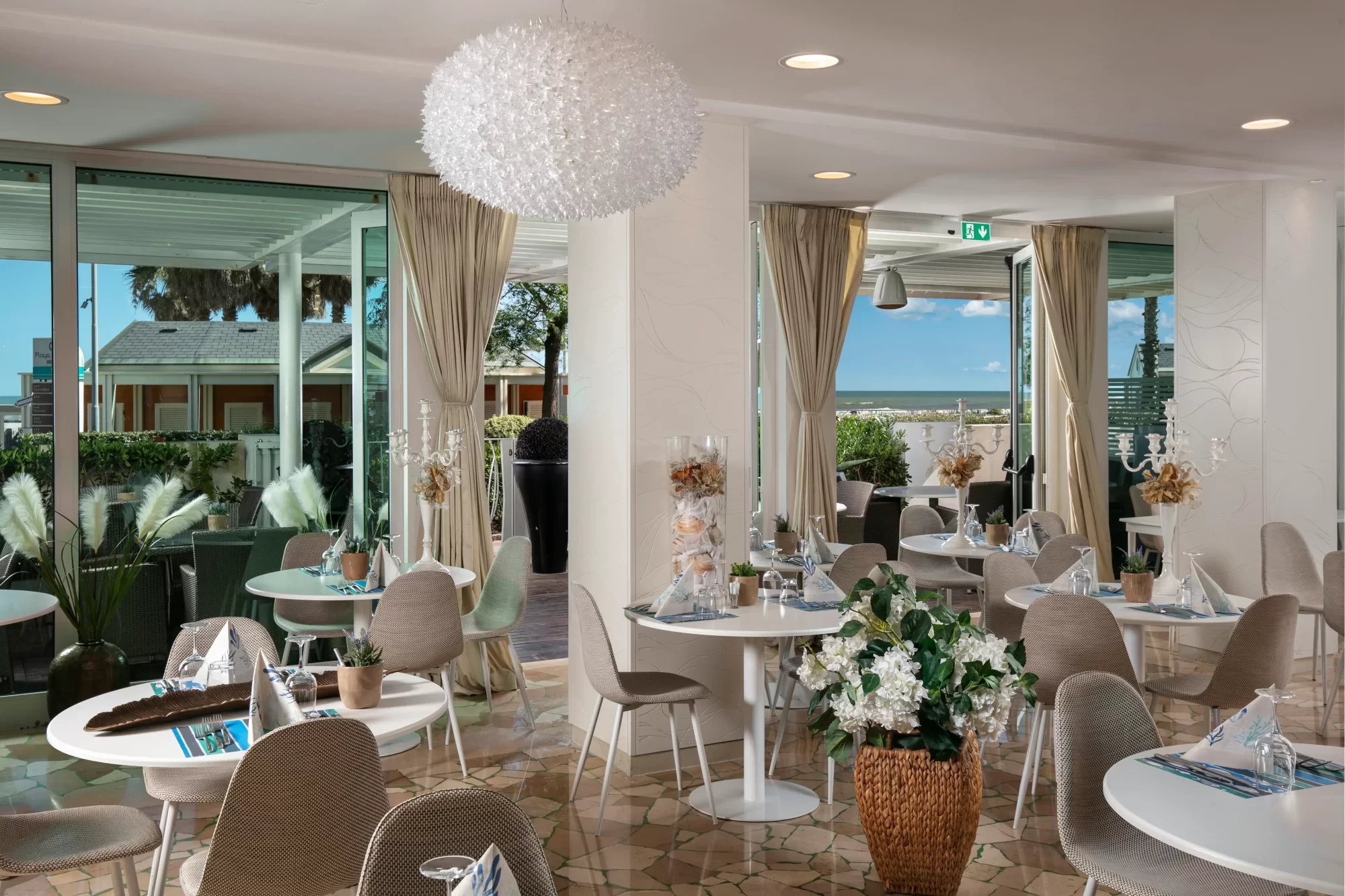 Moderner, eleganter Speisesaal mit Blick auf eine Terrasse und das Meer.
