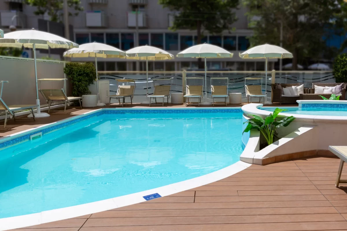 Piscina all'aperto con lettini e ombrelloni su una terrazza soleggiata.