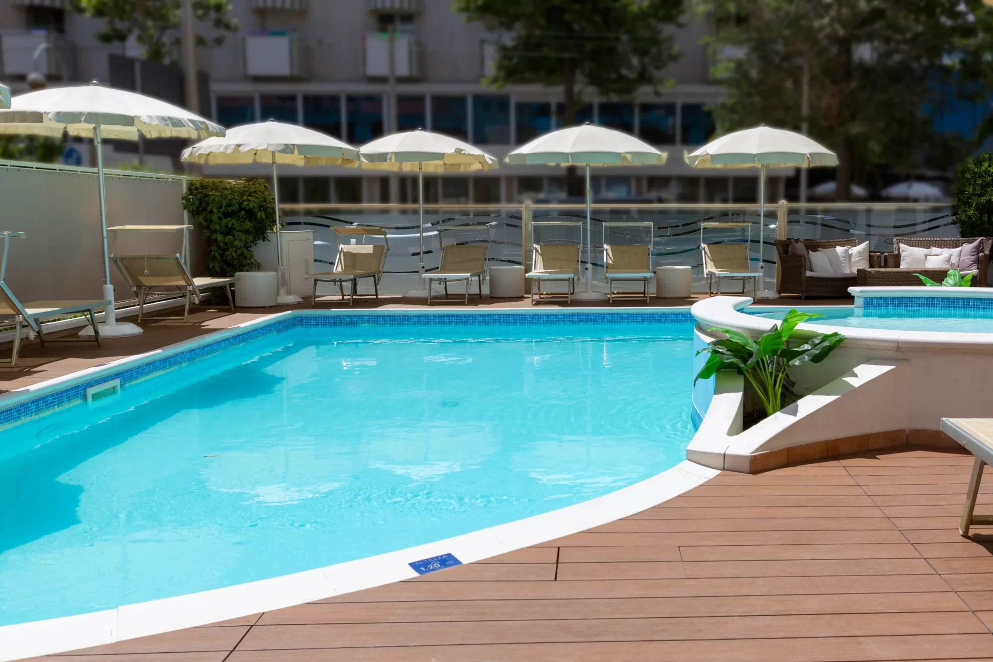 Piscina all'aperto con lettini e ombrelloni su una terrazza soleggiata.