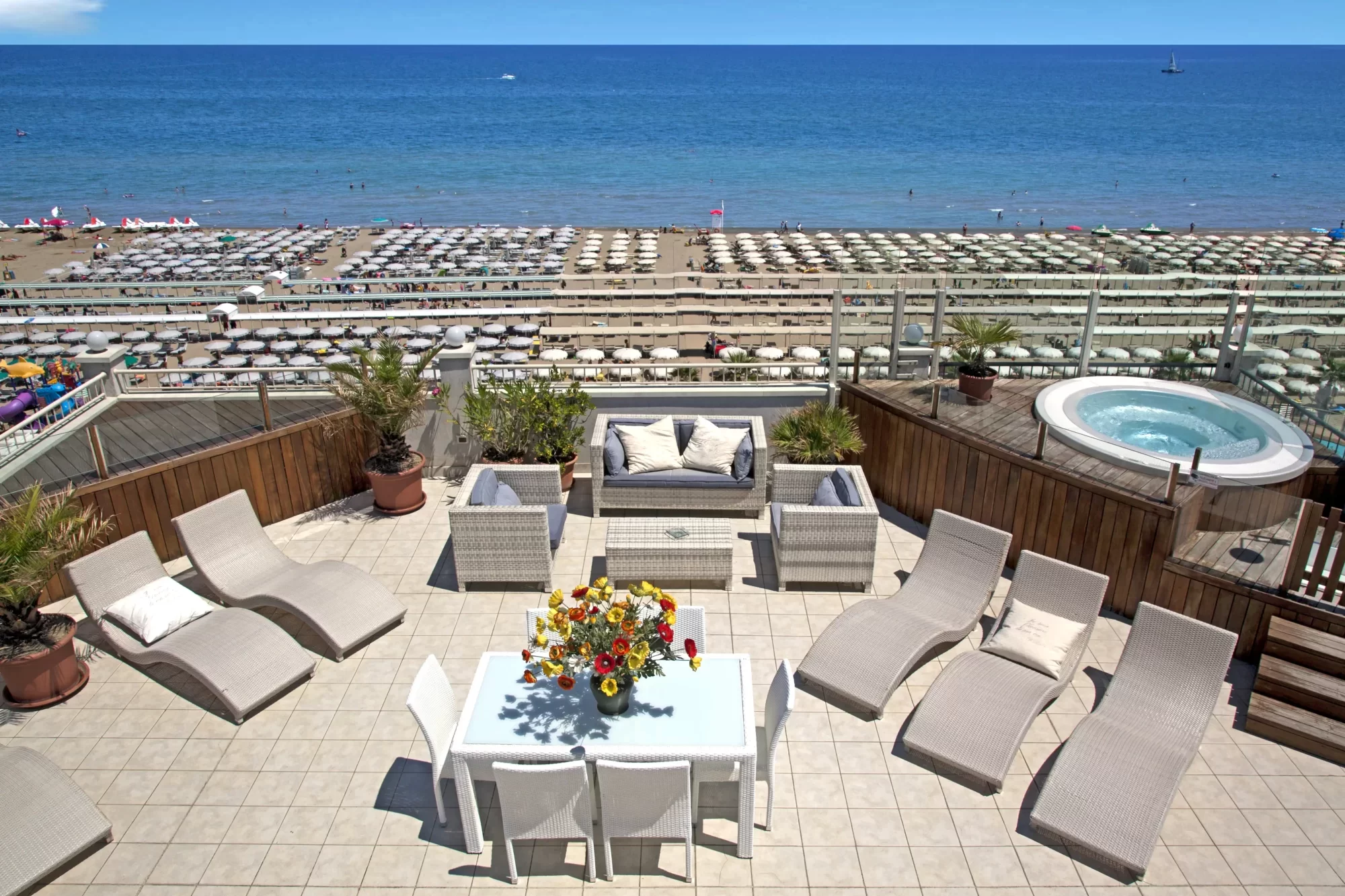 Terrazza arredata con vista sulla spiaggia e sul mare blu.