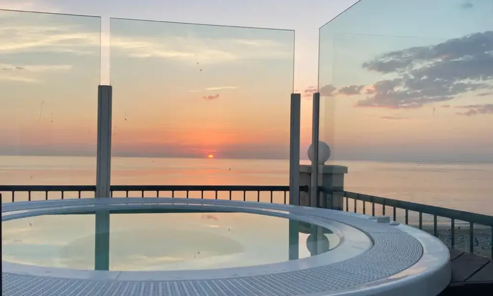 Vasca idromassaggio su terrazza con vista sul tramonto sul mare.