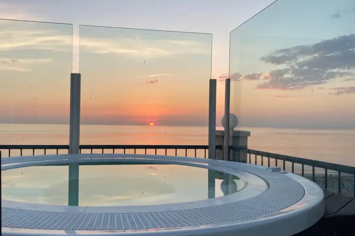 Ein Whirlpool auf einer Terrasse mit Blick auf einen Sonnenuntergang über dem Meer.