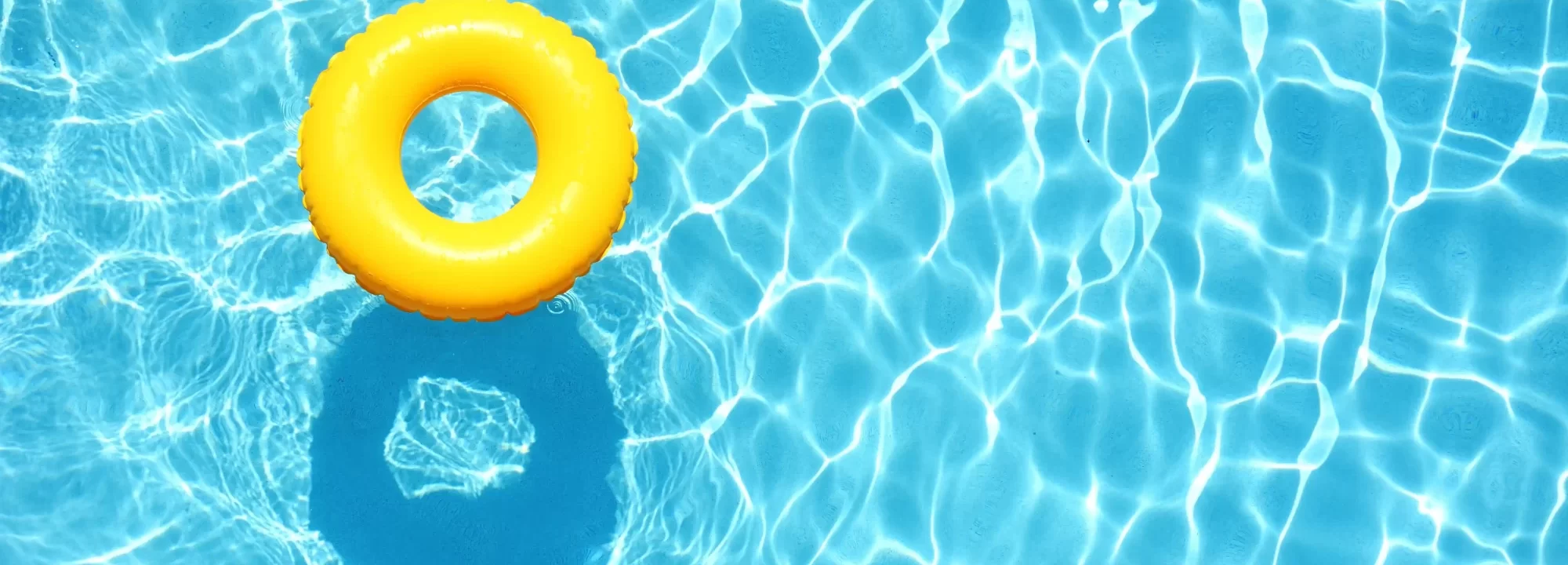 Ciambella gialla galleggiante in una piscina azzurra.
