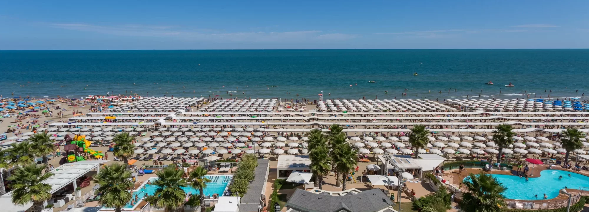 Spiaggia affollata con ombrelloni e bagnanti lungo la costa.