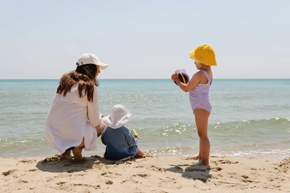 Una donna con due bambini piccoli gioca sulla spiaggia vicino al mare.