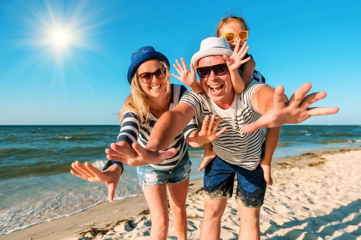 Famiglia felice in posa sulla spiaggia sotto il sole.
