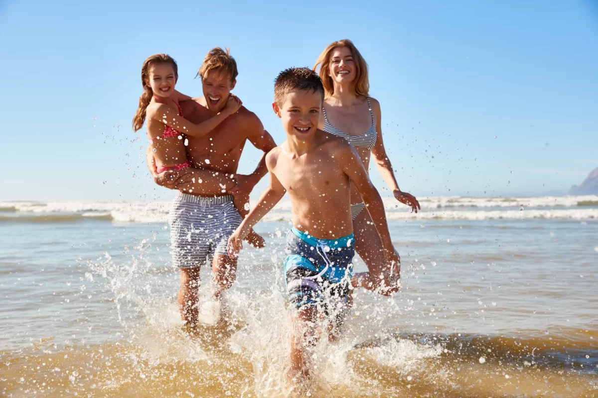 Famiglia felice gioca e corre sulla spiaggia al mare.