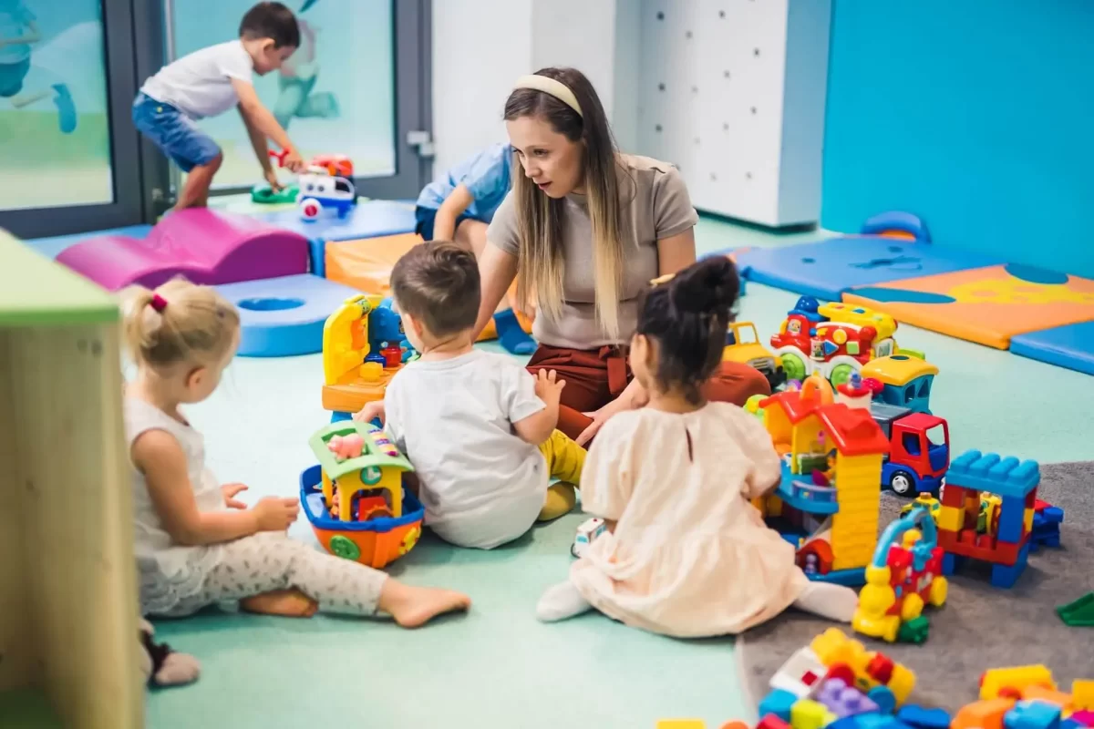 Una maestra gioca con bambini e giocattoli colorati in un asilo nido.