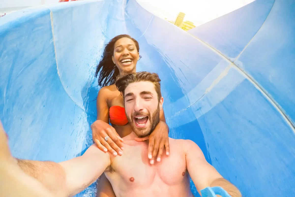 Coppia sorridente che si diverte su uno scivolo d'acqua in un parco acquatico.