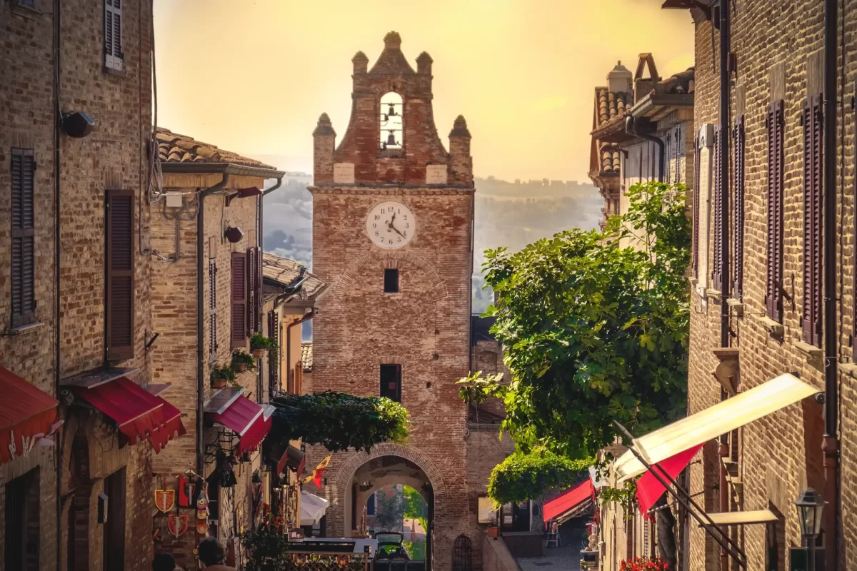 Scorcio di un borgo italiano con una torre dell'orologio e strade in pietra.