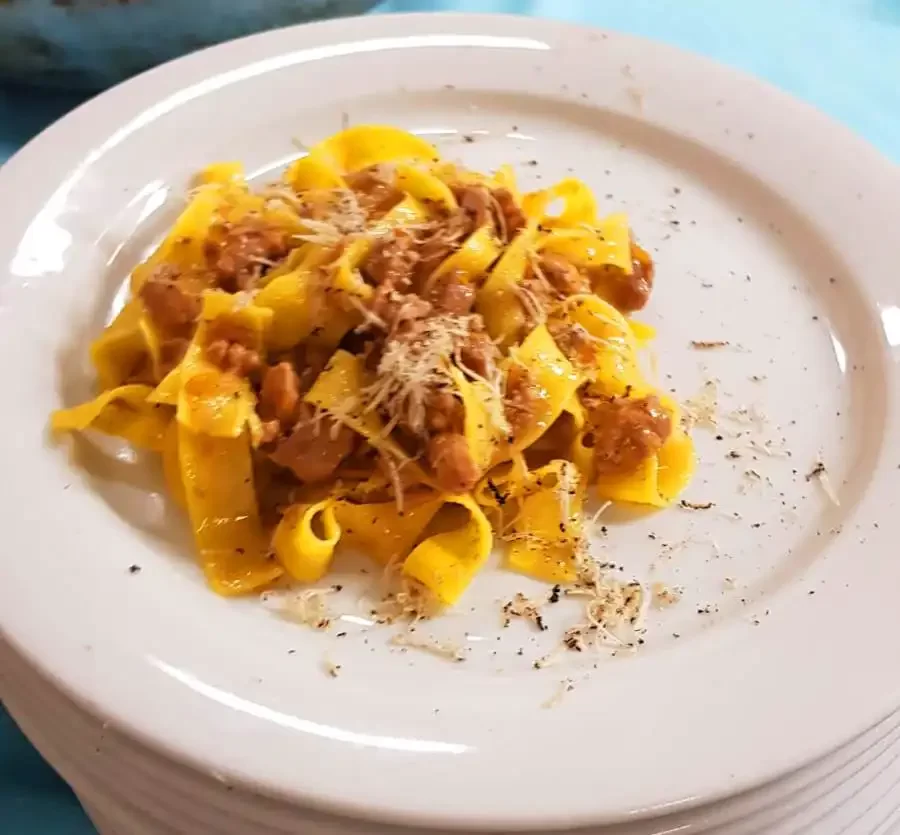 Un piatto di tagliatelle al ragù servito su un piatto bianco.
