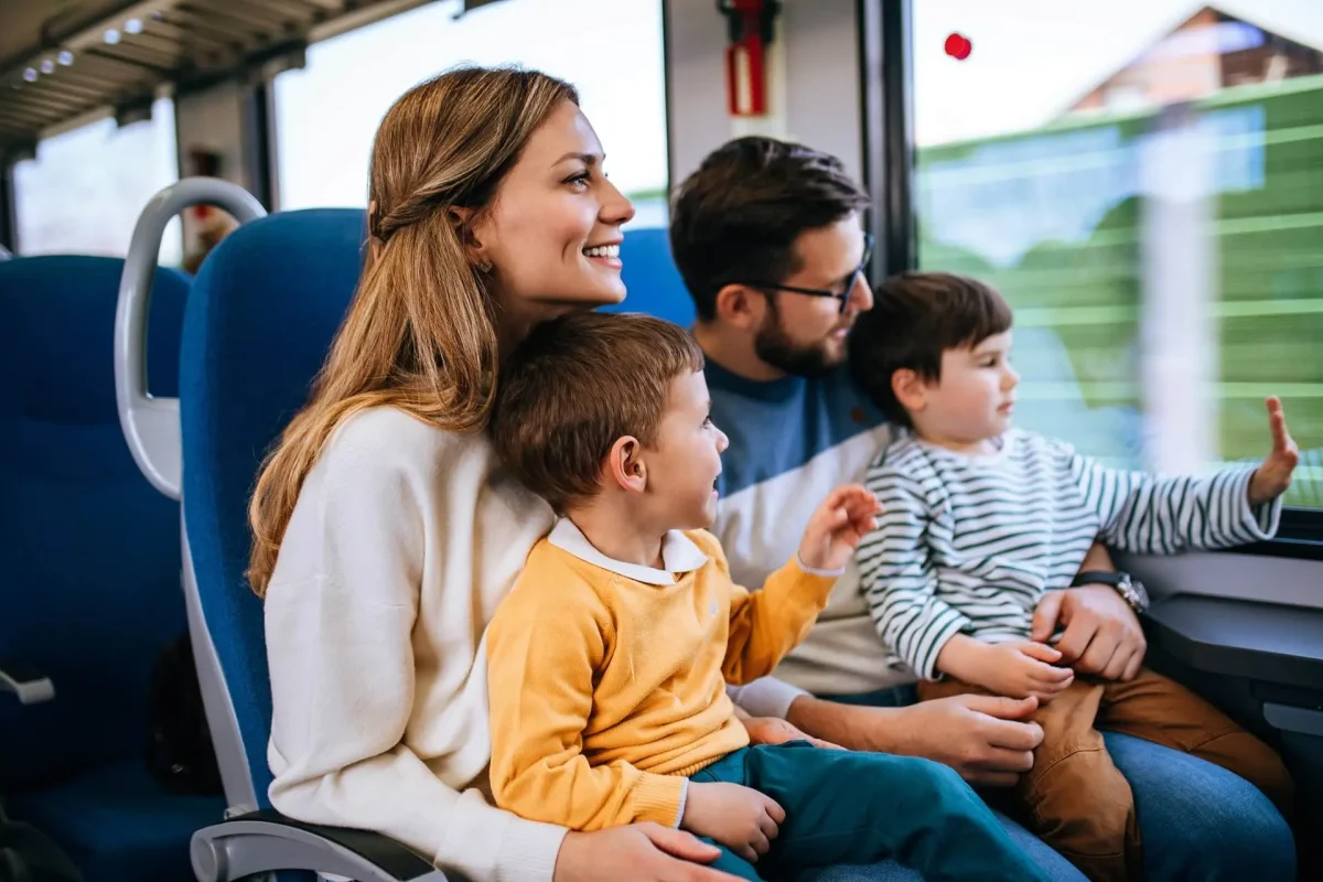 Famiglia seduta su un treno che guarda fuori dal finestrino.